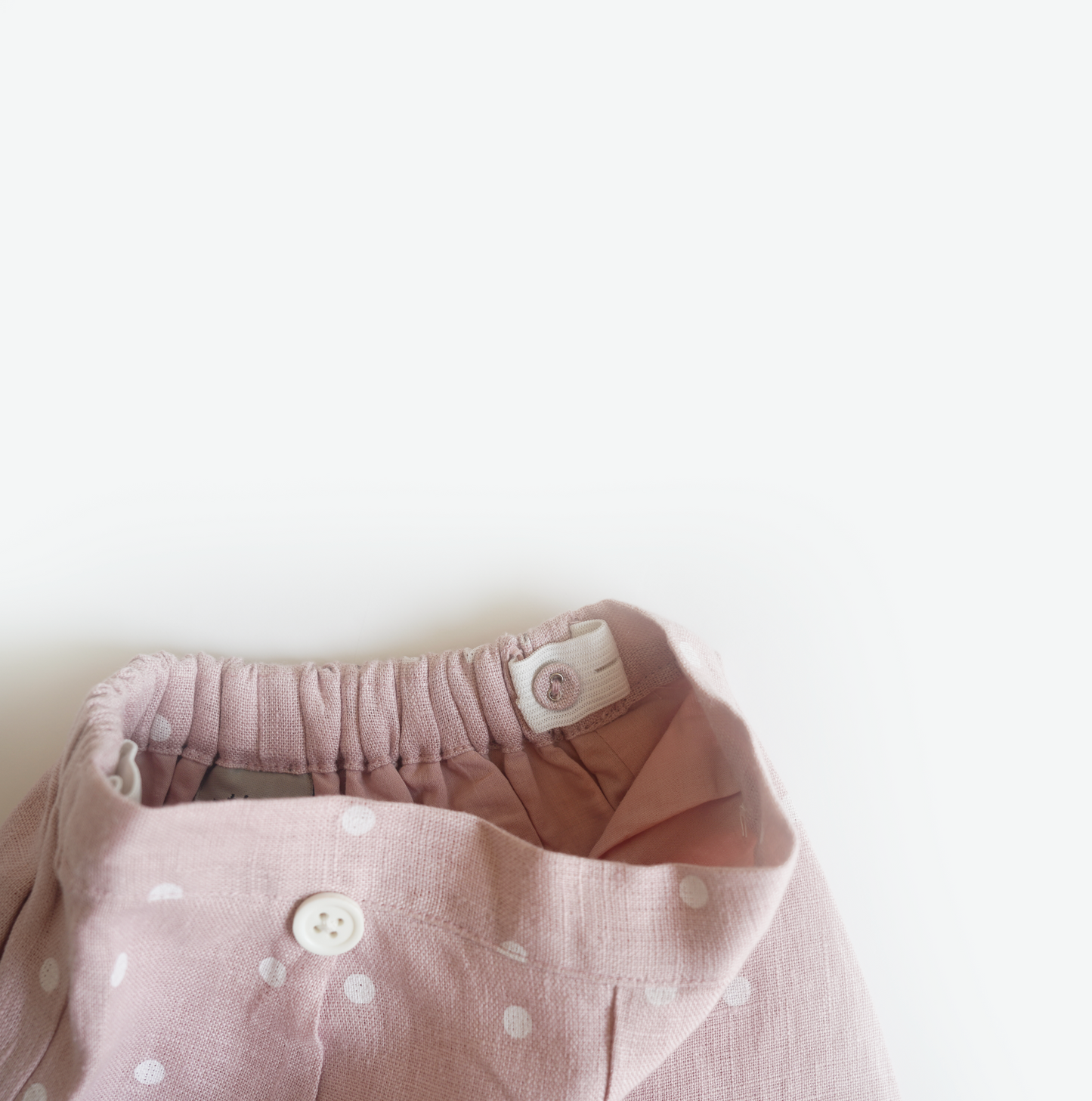 Pink hand embroidered polka dot shorts and top set in pure linen fabric, featuring floral embroidery and matching bow for children’s wear.