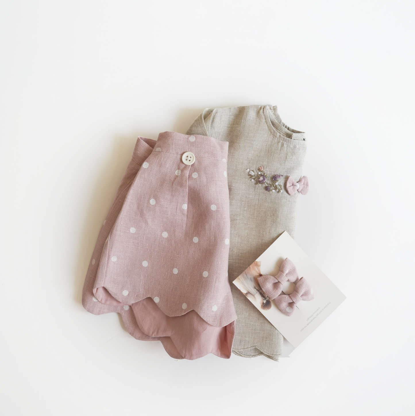 Pink hand embroidered polka dot shorts and top set in pure linen fabric, featuring floral embroidery and matching bow for children’s wear.