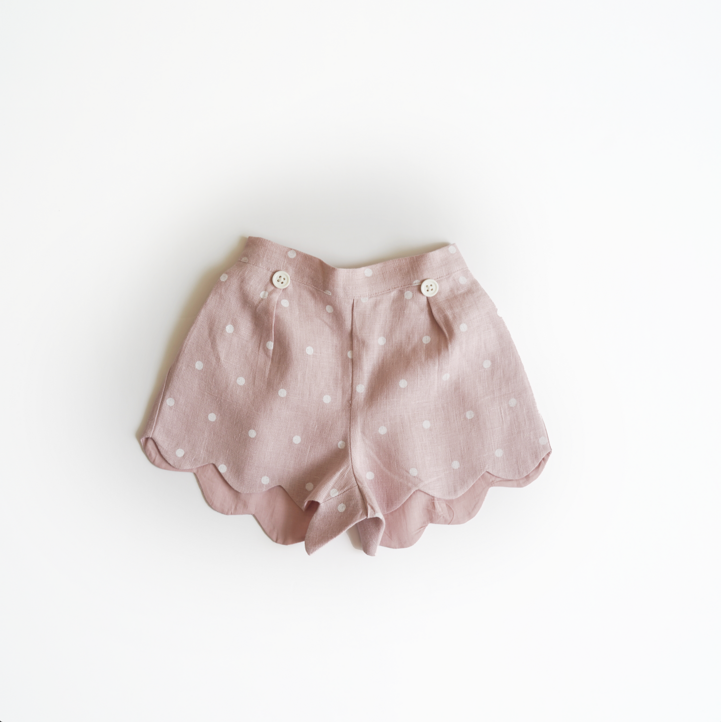 Pink hand embroidered polka dot shorts and top set in pure linen fabric, featuring floral embroidery and matching bow for children’s wear.
