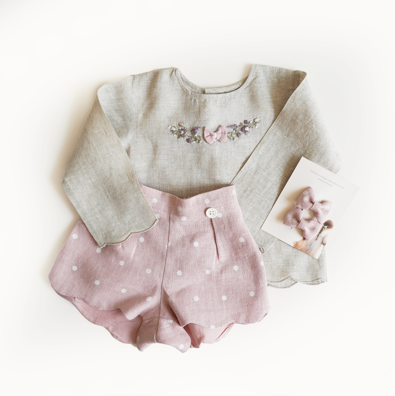 Pink hand embroidered polka dot shorts and top set in pure linen fabric, featuring floral embroidery and matching bow for children’s wear